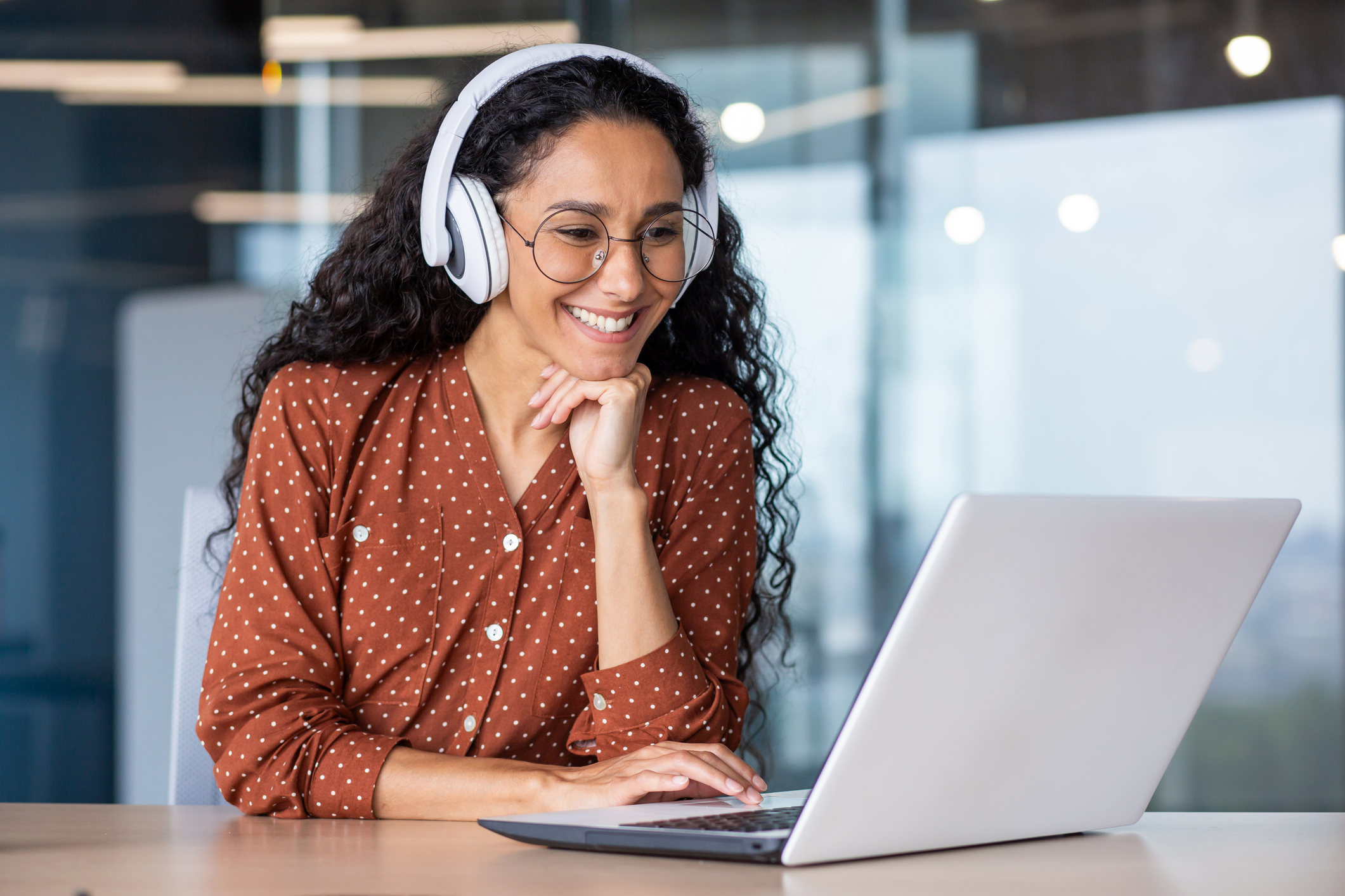 Woman Smiling Looking At A Computer with Headphones